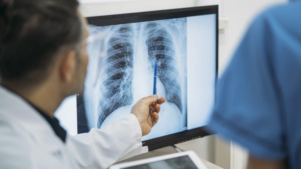 Two medical staff look at an X-ray of a human torso