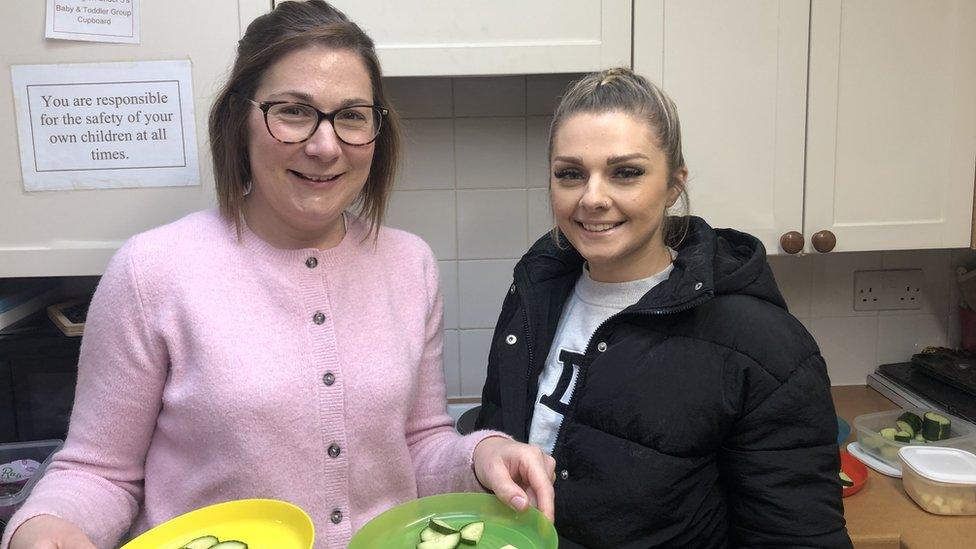 Kathryn Brand and Ashleigh Fox stand in a kitchen, smiling at the camera