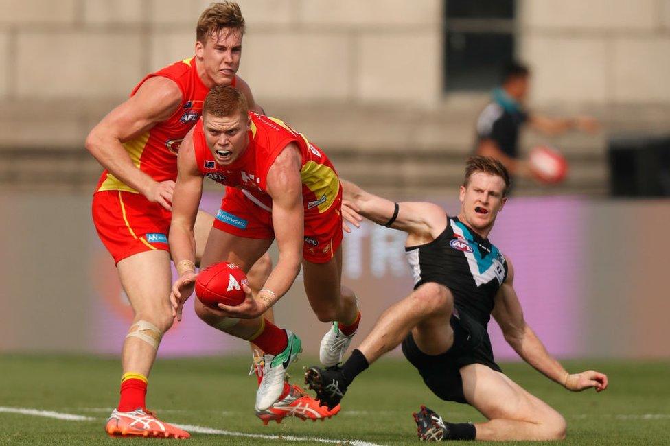 Tom Lynch of the Suns, Peter Wright of the Suns and Tom Jonas of the Power in action