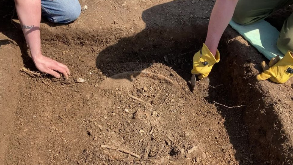 Digging in the mud - with what looks like a bike wheel being uncovered