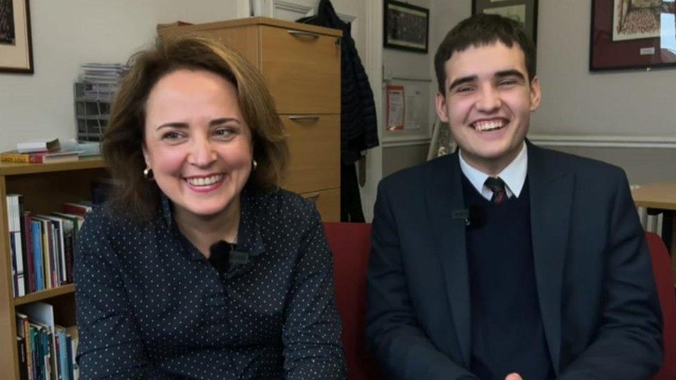 David, wearing school uniform, and his mother, looking at the screen