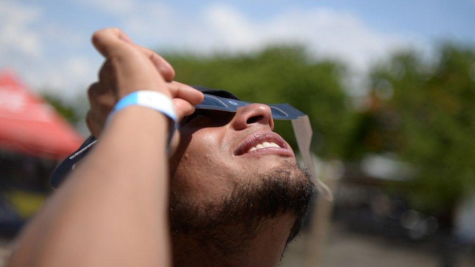 Man viewing eclipse through protective glasses.