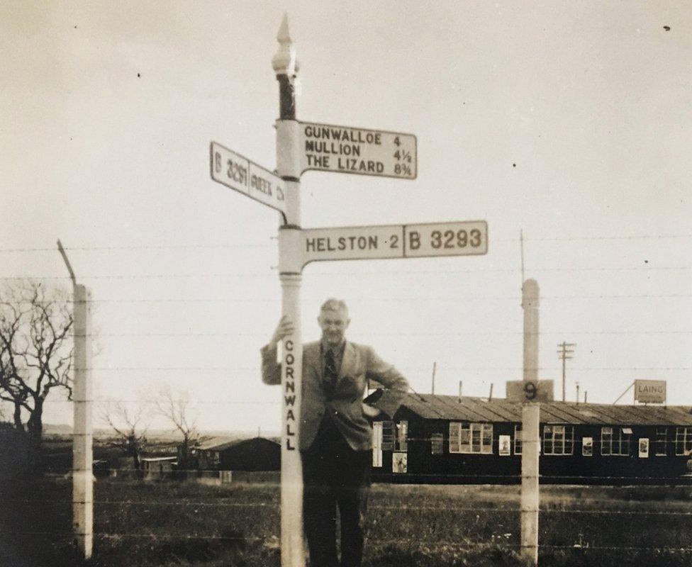 A man standing next to an old signpost