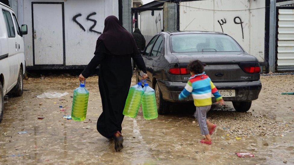 Woman collecting water with a child