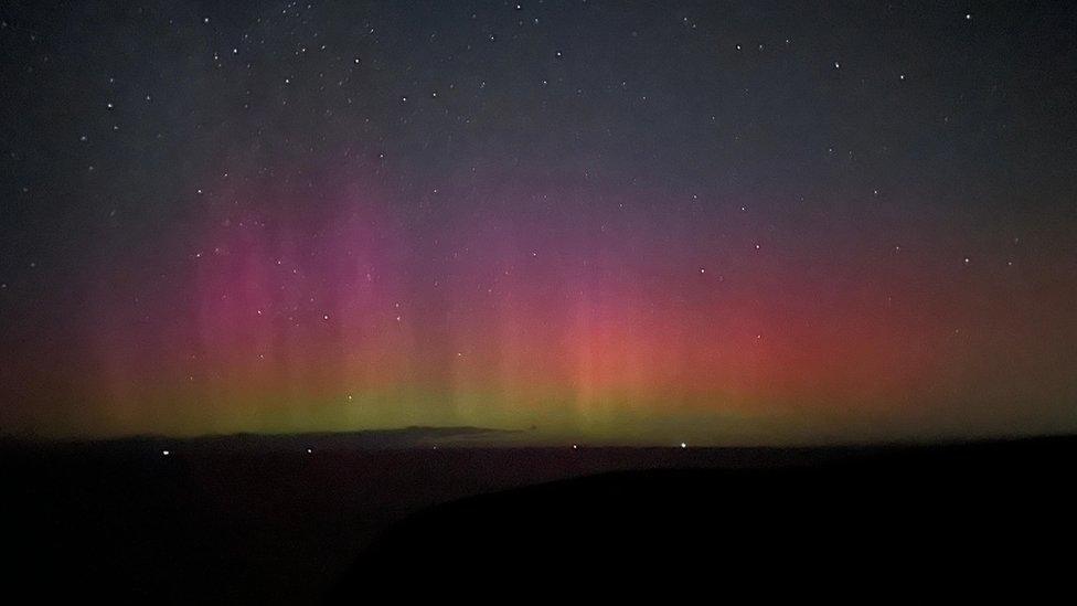 Night sky filled with shafts of purple and green light.