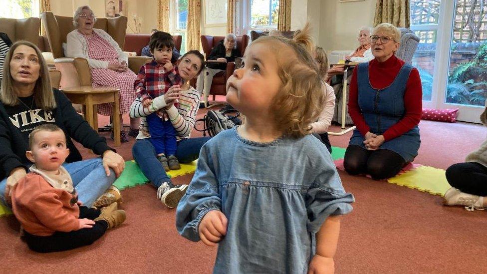 Children, carers and care home patients taking part in a music class