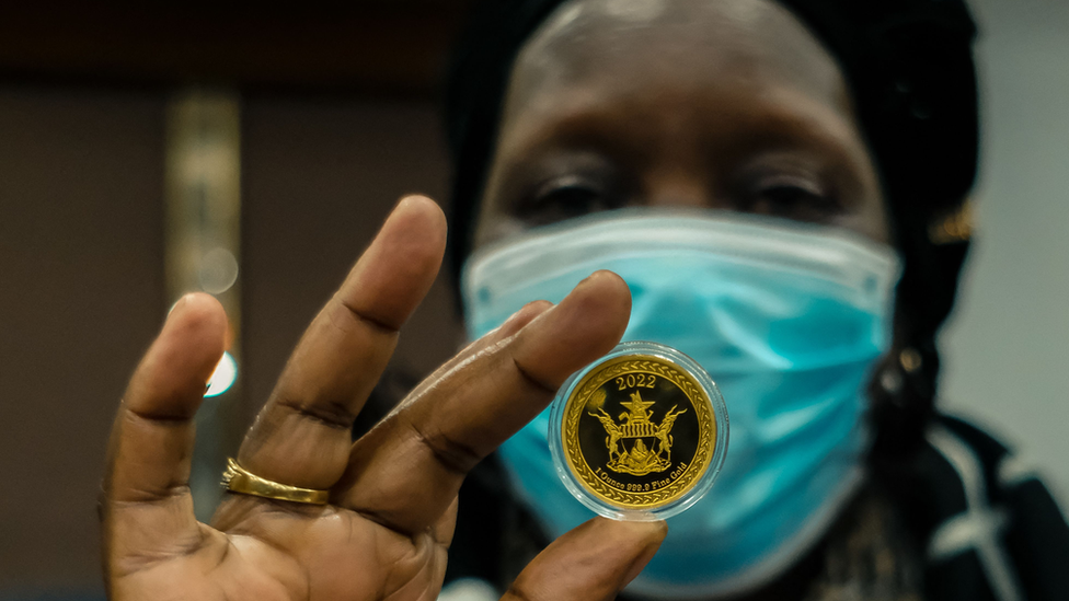 A woman holds a cold coin in her hand