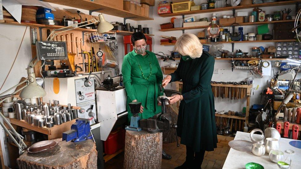 The Duchess of Cornwall attempts silversmithing during a visit to Cara Murphy's workshop