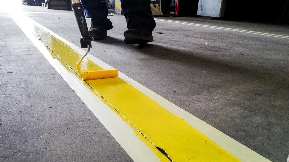 Workman painting parking lines on a road