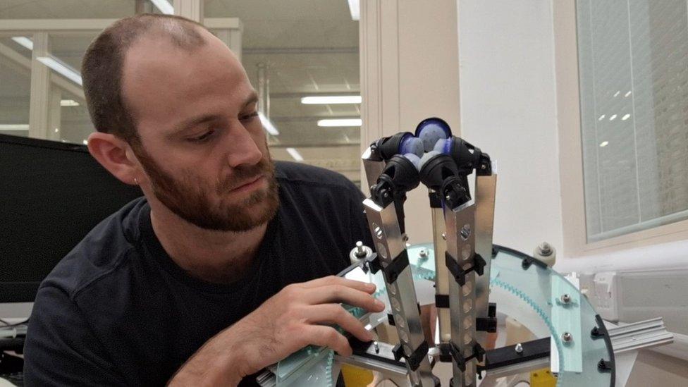 Man stares at robot clamp which could help breast examinations