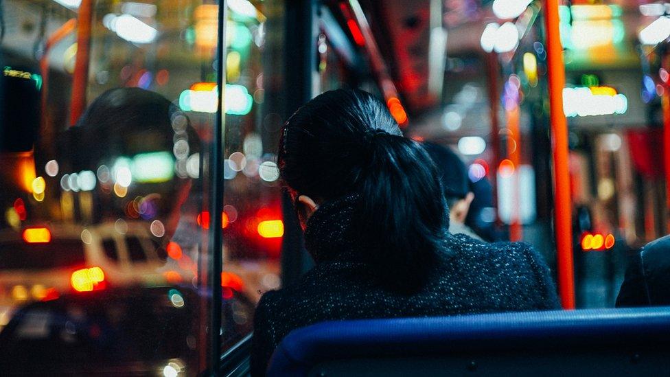 A woman sitting on a bus at night