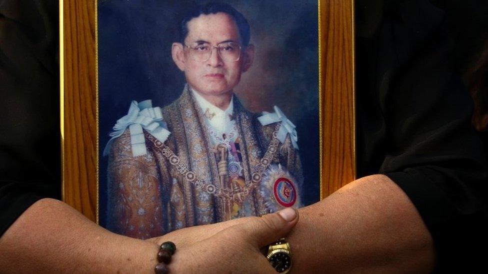 A mourner holds a portrait of Thailand"s late King Bhumibol Adulyadej in Bangkok, Thailand