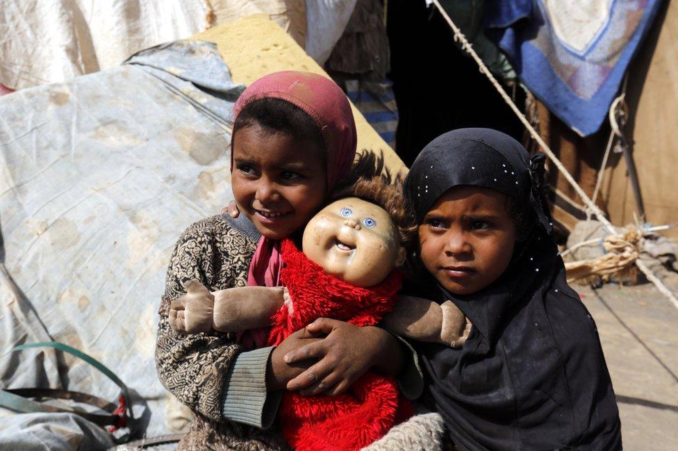 Two children hold their doll