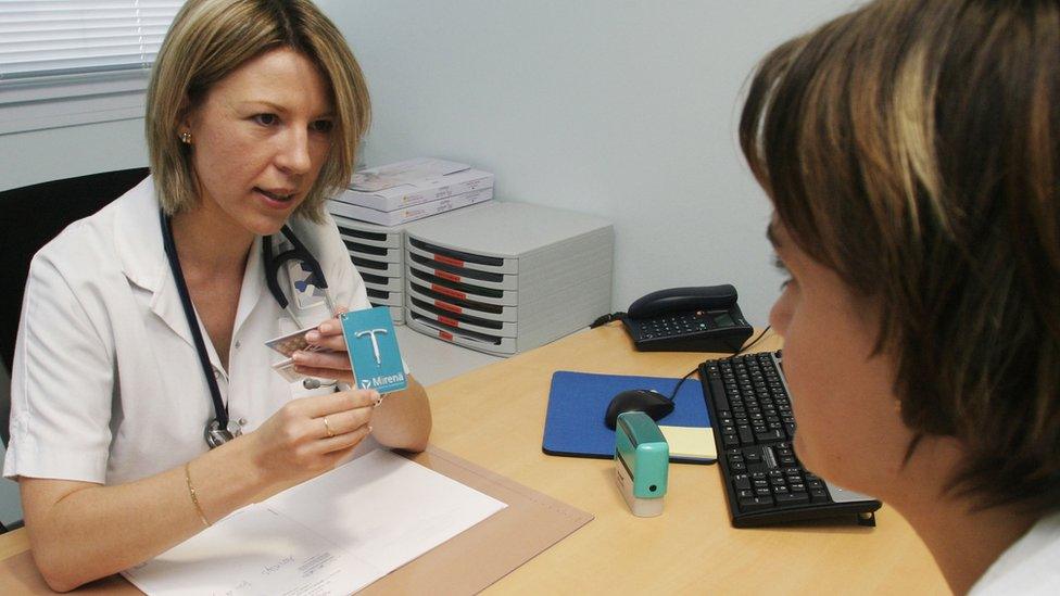 doctor showing patient a mirena coil- birth control