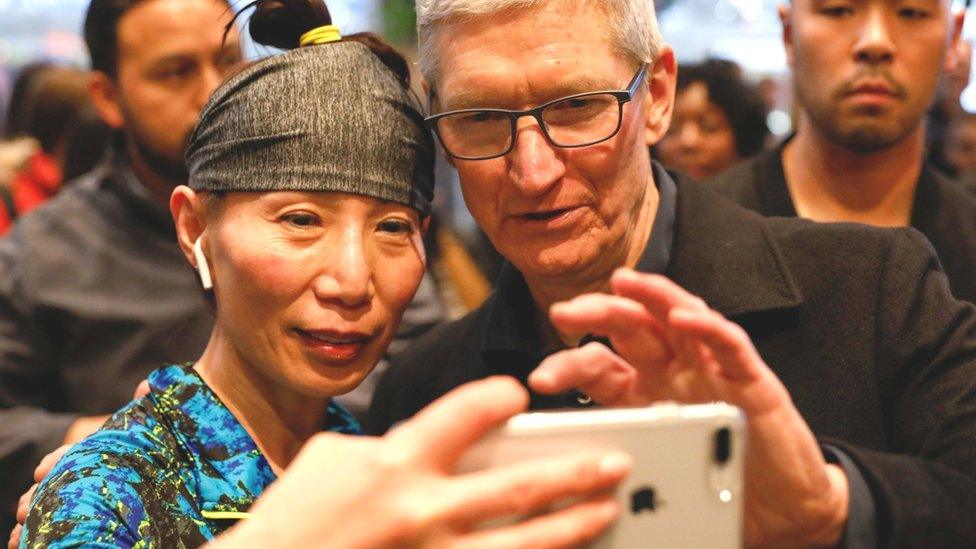 A woman takes a selfie with Apple chief executive Tim Cook