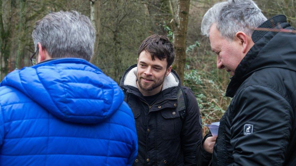 John E Fry and Richard Bazly with their back to the camera and actor Connor Wulfric