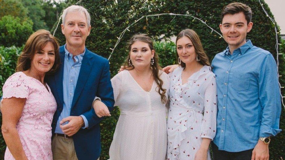 Two adults and three teenage children smile at the camera