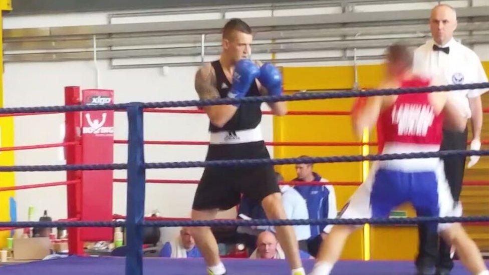 Daniel (in blue) in the boxing ring with an opponent