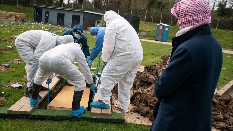 A mourner watches as the coffin is lowered into the ground during the funeral in the Eternal Gardens Muslim Burial Ground, Chislehurst of Ismail Mohamed Abdulwahab