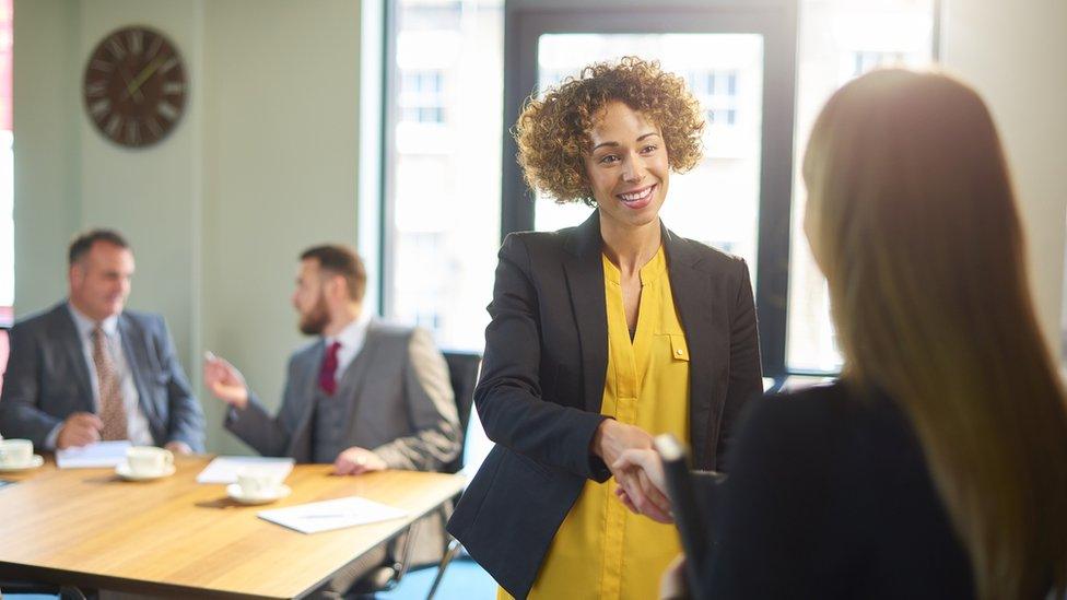 Women shaking hands in boardroom