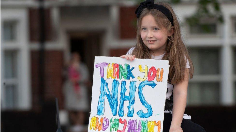 Girl holds sign saying thank you and my mummy