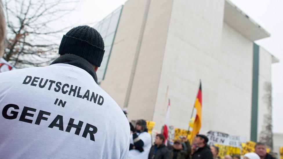 "Germany in danger" is written on the T-shirt of a protester outside the German chancellery