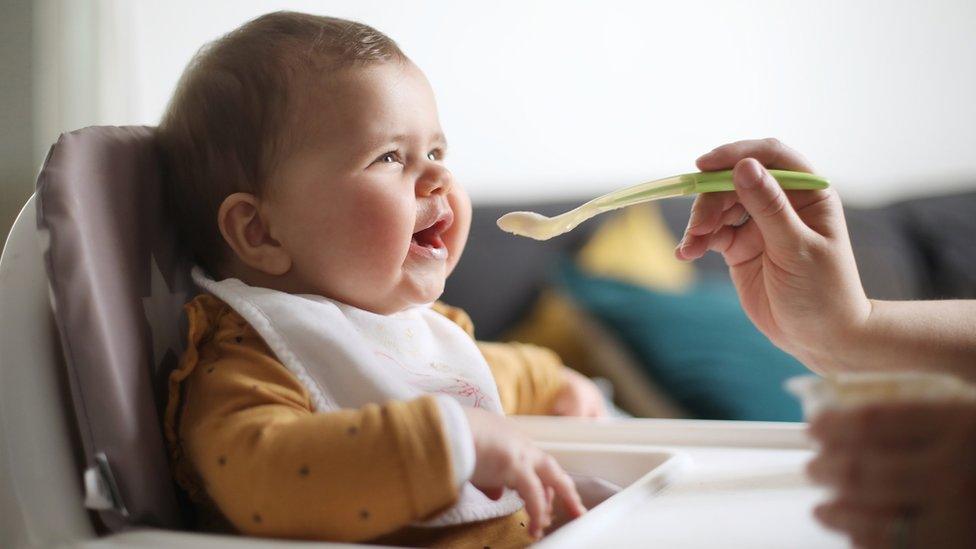 Baby girl giggling while offered food