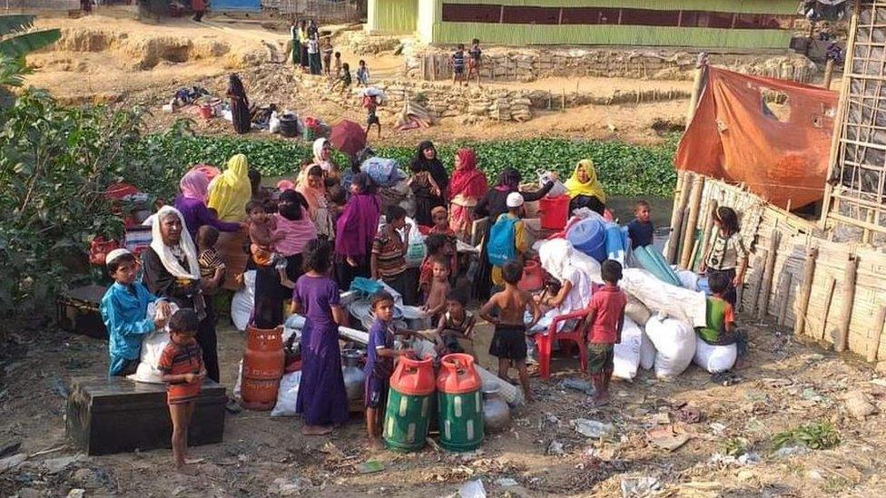 Children and women standing on a vacant plot of land