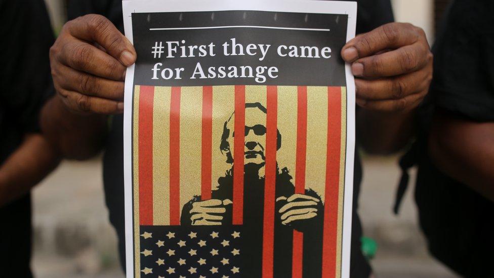 A protester showing Assange behind bars with: 'First they came for Assange'