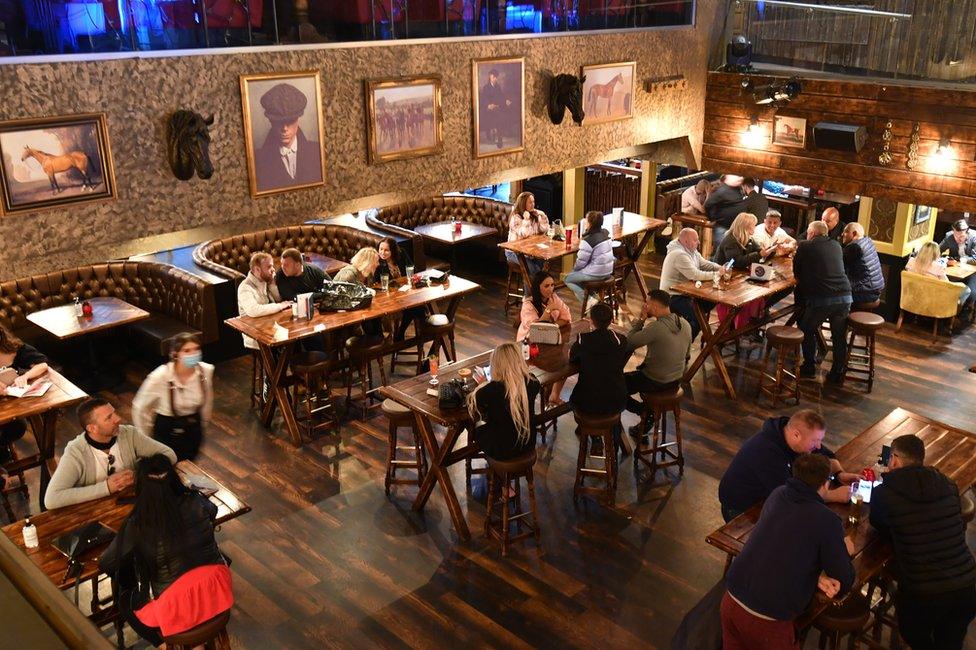 People drink together in a bar in Manchester on 17 May, following the easing of lockdown restrictions