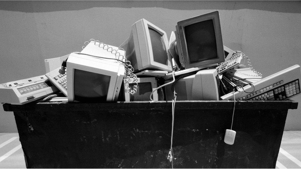 Old computers in a large waste bin