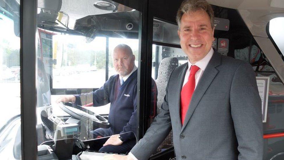 Dan Norris on a bus with a driver sitting behind him