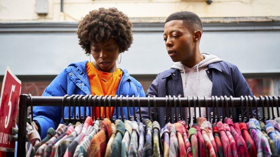 Two friends looking at a rack of clothes in a market