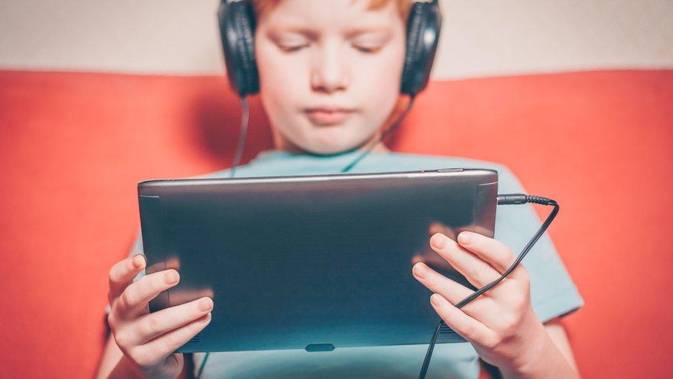 Redhaired boy on a tablet.