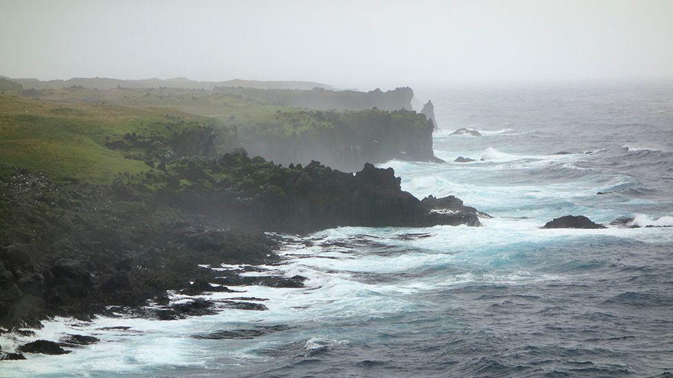 The wind and waves create a salty spray that disperses over the coast