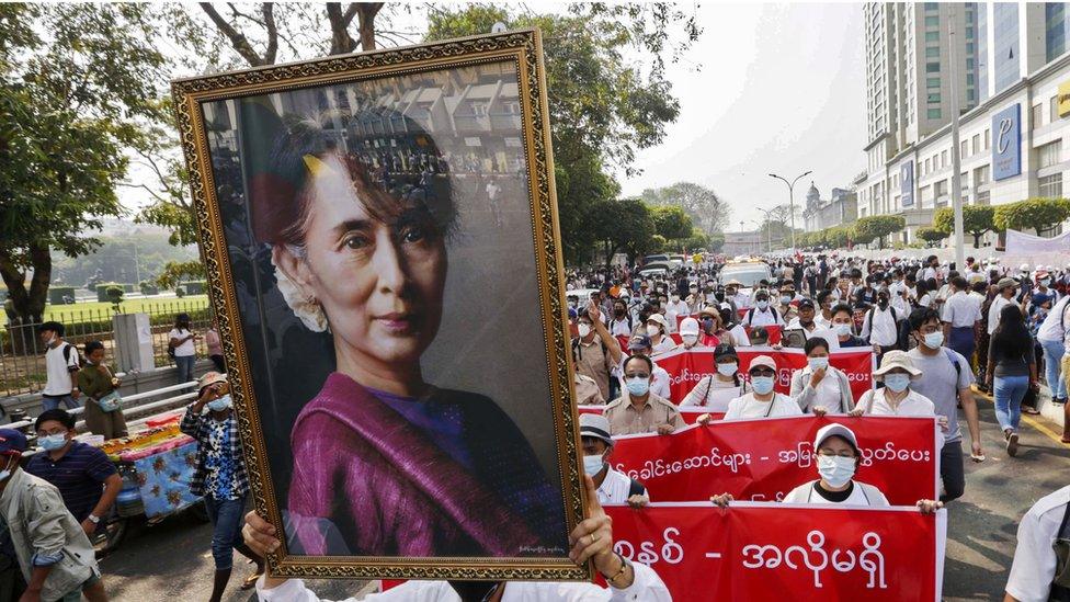 Protesters hold up a photo of Aung San Suu Kyi