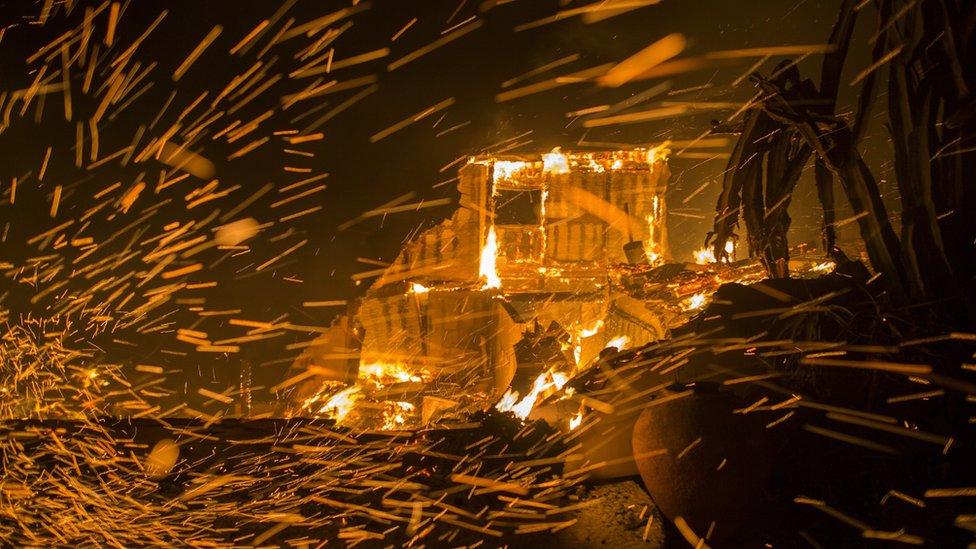 Strong winds blow embers from burning houses during the Woolsey Fire on November 9, 2018