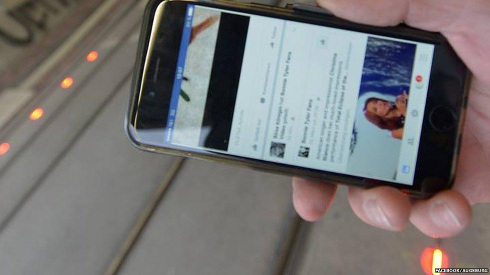 Hand holding smartphone in front of tracks and red lights