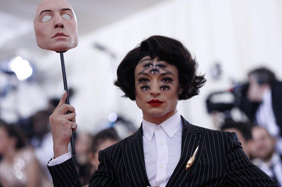 Ezra Miller holds up a mask