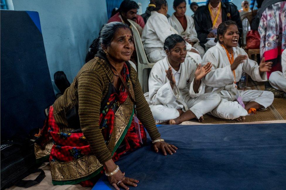 A woman watches from the sidelines