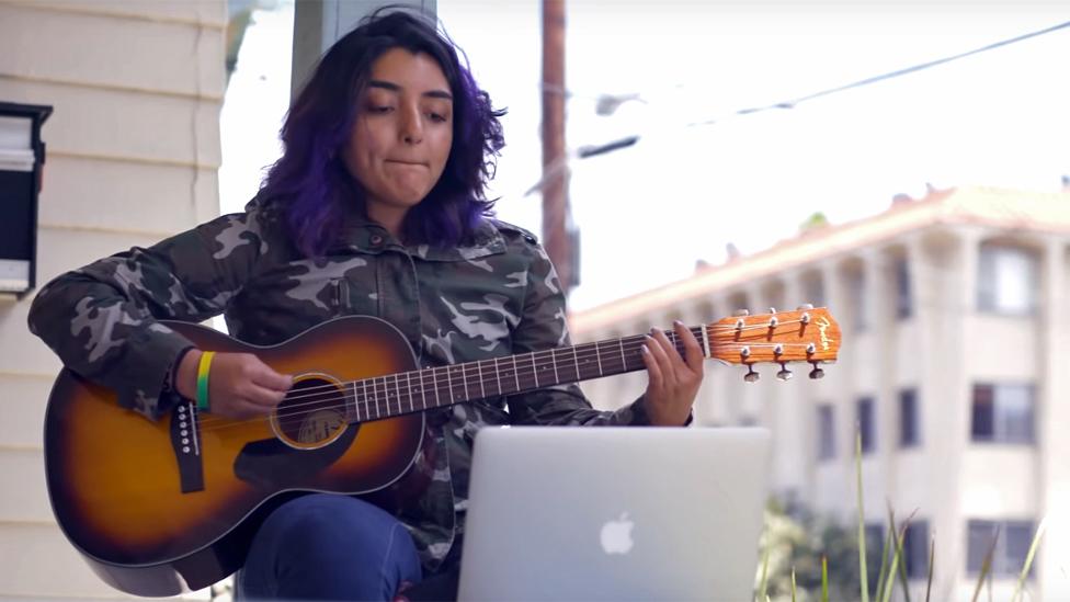 A young woman learning to play guitar