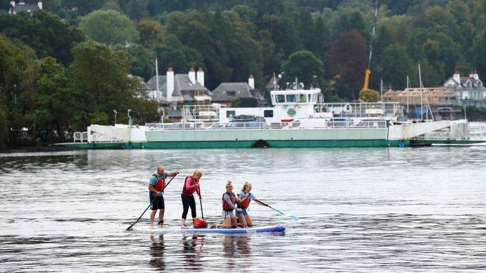 Family paddle boarding during summer in Windermere