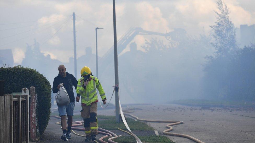 Man being led down the street after being evacuated from his home