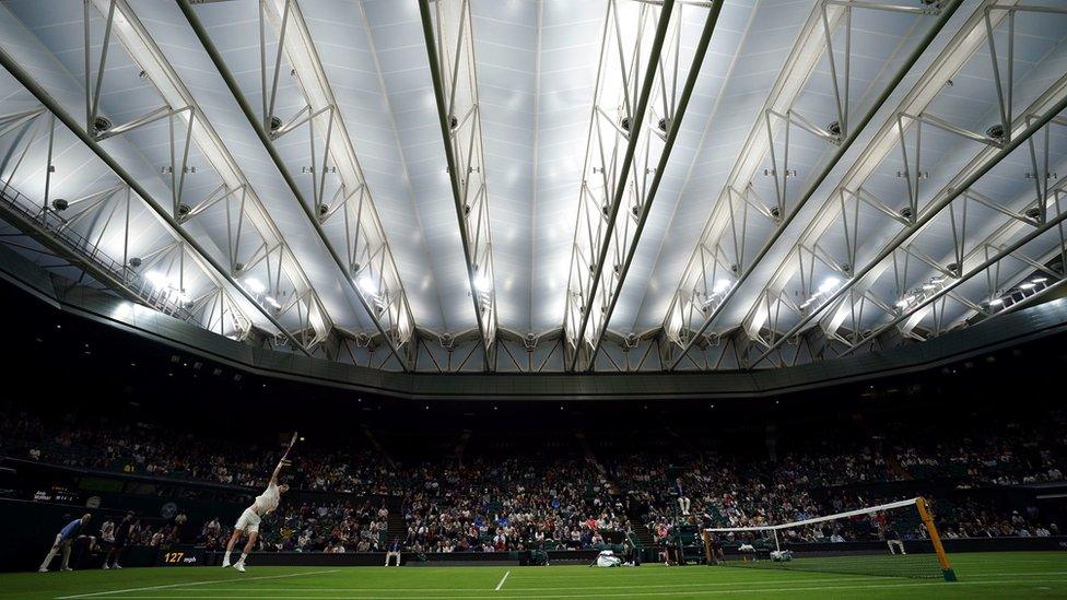 Andy Murray plays tennis under the closed roof of Wimbledon Centre Court