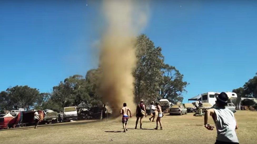 Revellers run towards a dust whirlwind at an dance music festival in Australia.