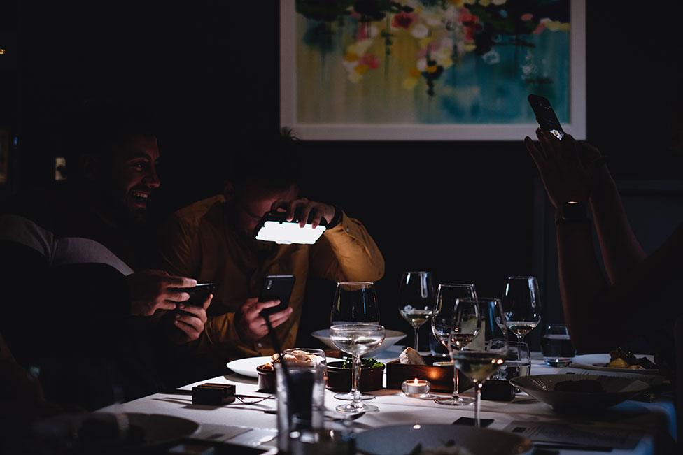 Two men take photos of the their food in a restaurant