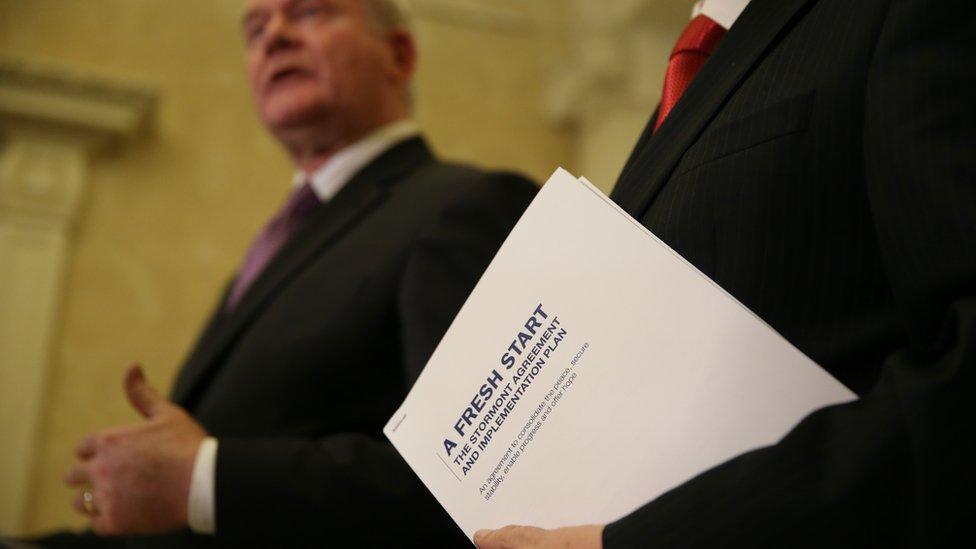 First Minister Peter Robinson holds a copy of the agreement as he speaks alongside Deputy First Minister Martin McGuinness