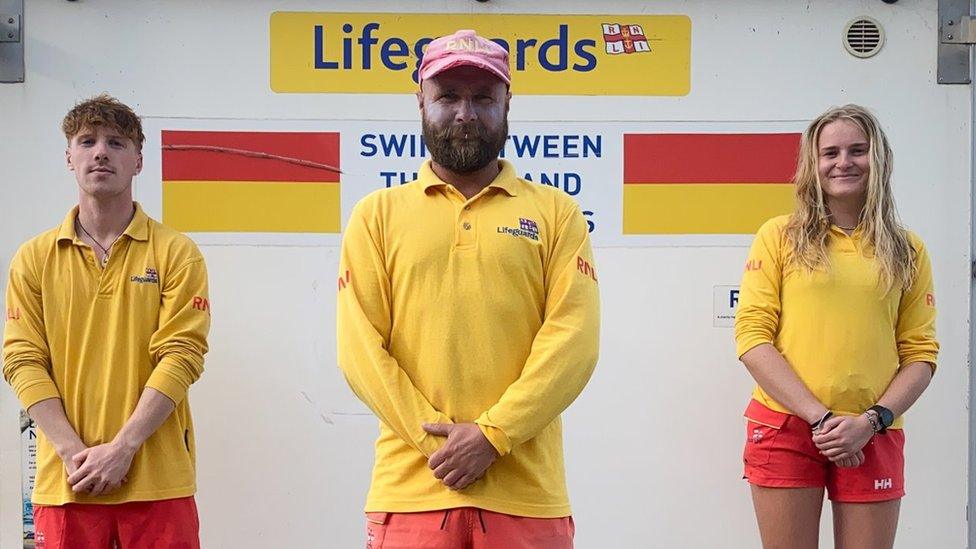 Three life guards (two men and one woman) in yellow shirts