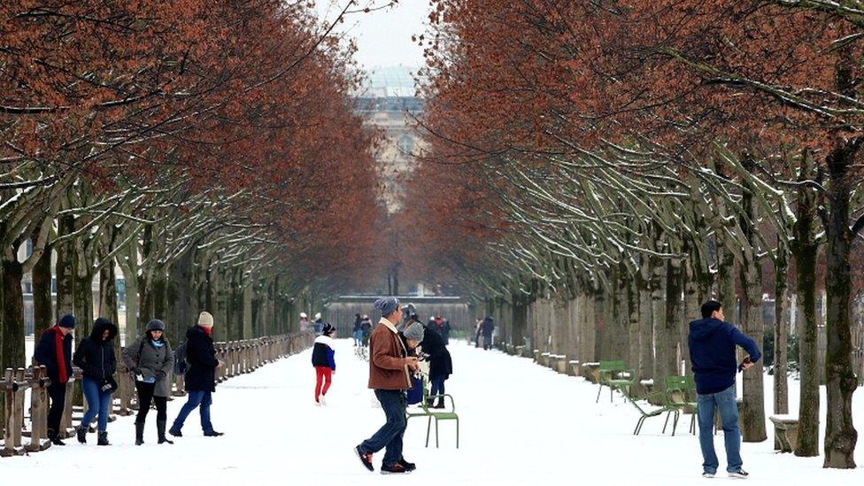 People walk in the snow-covered Tuileries Garden in Paris, as winter weather hits the city on 22 January 2019