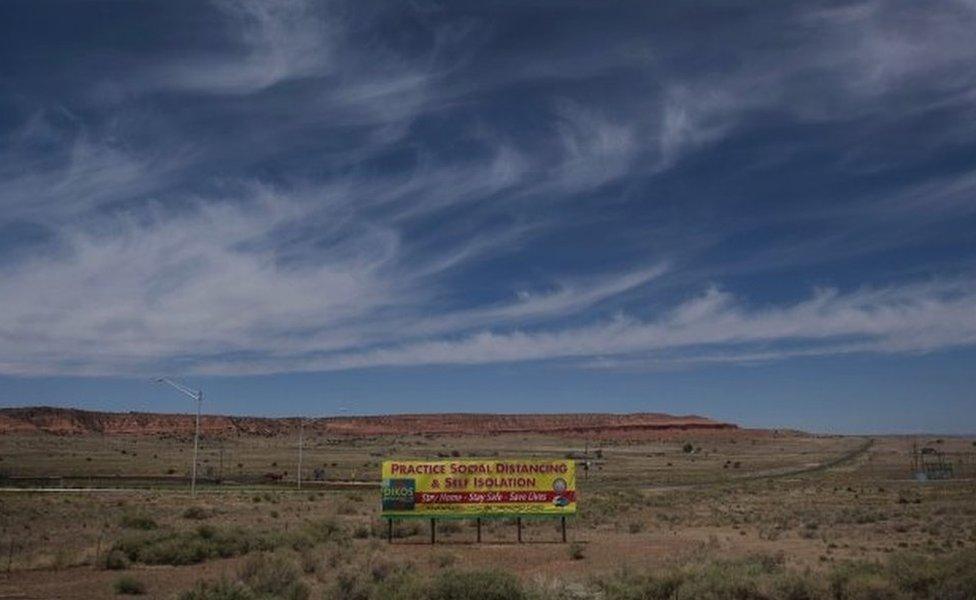 Sign in desert saying "practice social distancing and self-isolation"